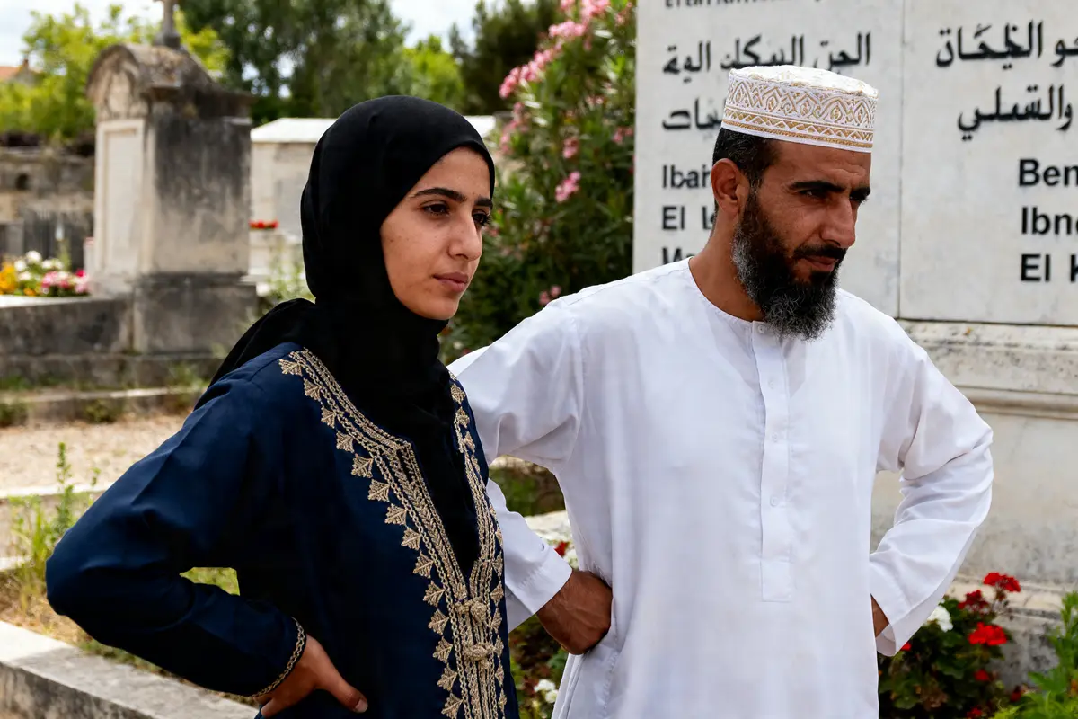 Un homme et une femme au cimetière près de tombes portant des noms de familles arabes