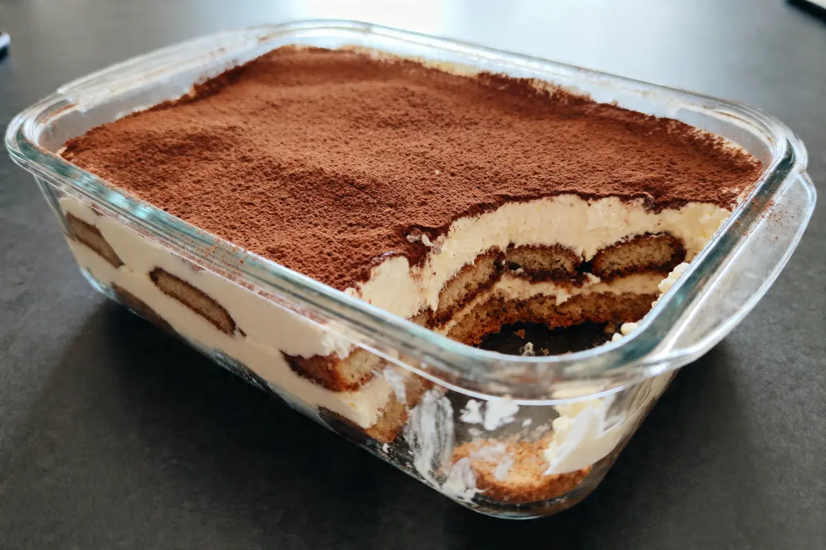 Tiramisu pour femme enceinte dans un plat en verre avec cacao saupoudré sur le dessus