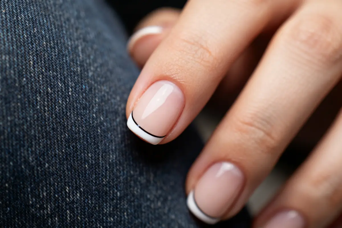 Manucure française élégante sur ongle court avec motif ligne fine sur fond jean