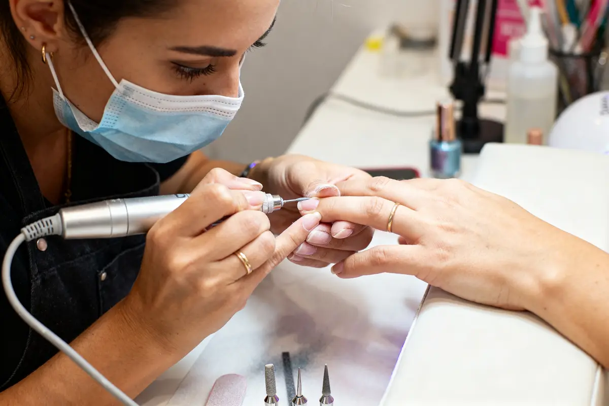 Esthéticienne réalise une manucure russe avec précision et outils dédiés en salon de beauté