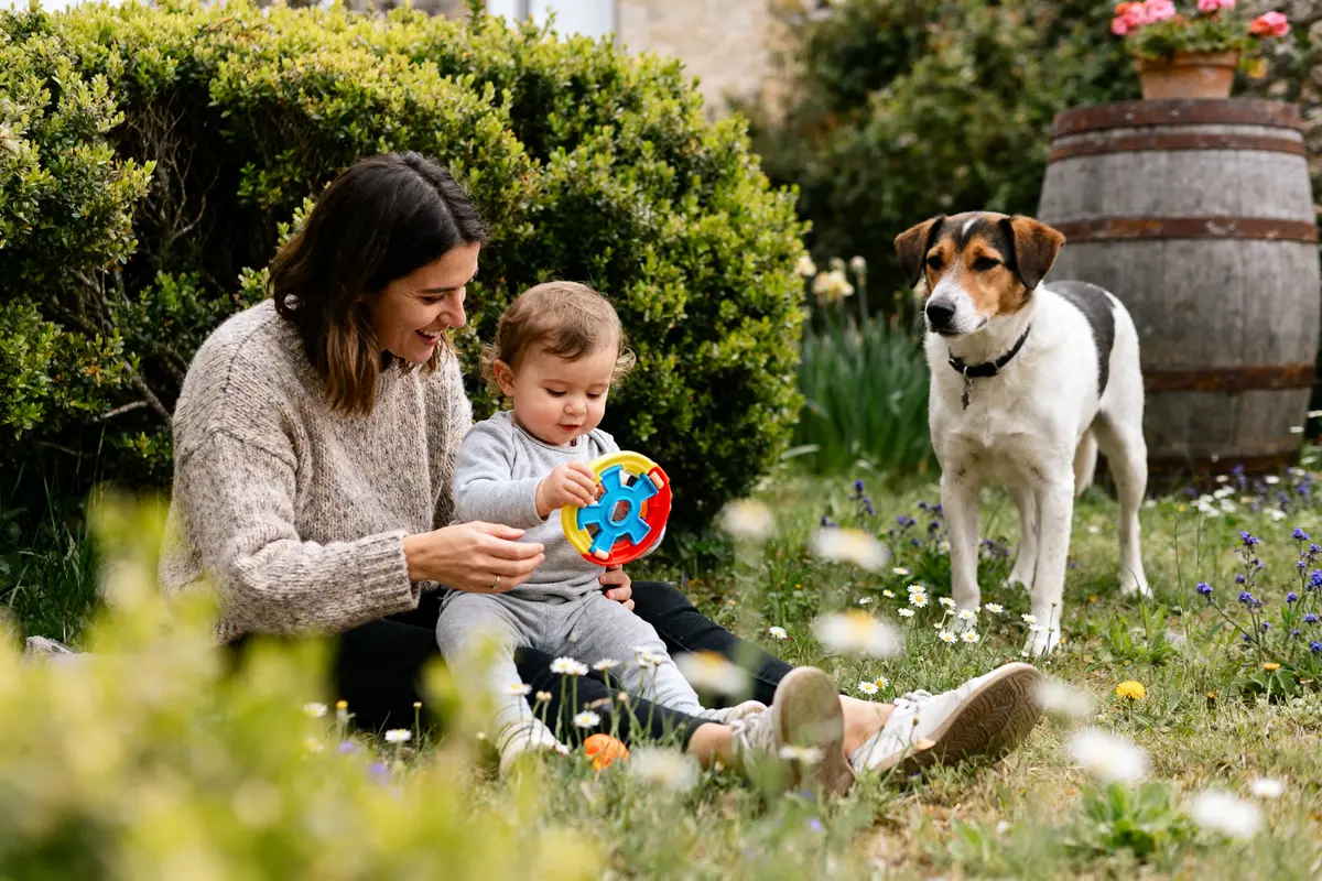 Une mère et son enfant jouent dans le jardin avec un chien petitpasparental blog